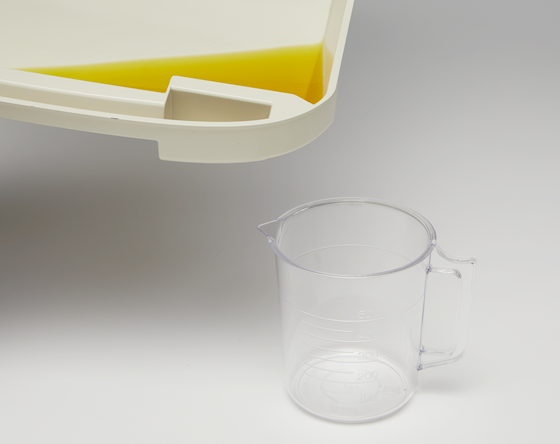 猫用システムトイレのトレーにたまったオシッコを容器に移し替える様子